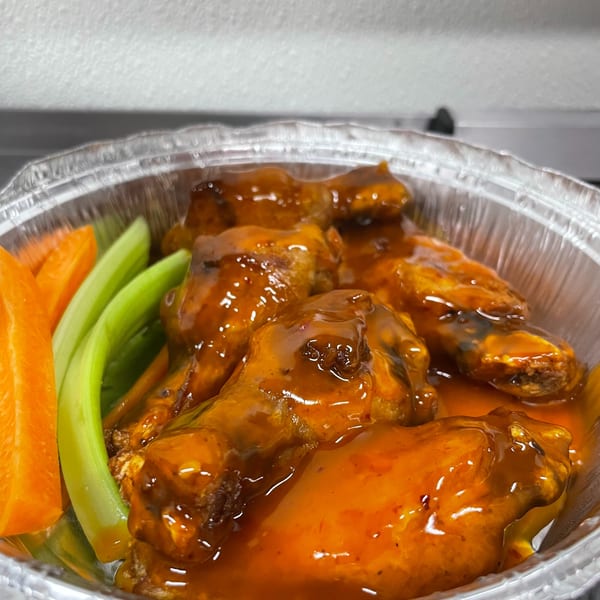 Grubbs Takeaway's buffalo wings with celery and carrot sticks in a foil container.