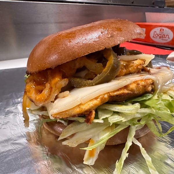 Grubbs Takeaway burger with chicken, melted cheese, jalapeños, onions, and lettuce on foil.