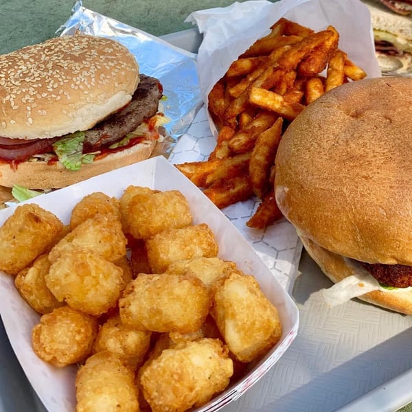 Two Grubbs Takeaway burgers, a side of crispy fries, and a container of golden tater tots.