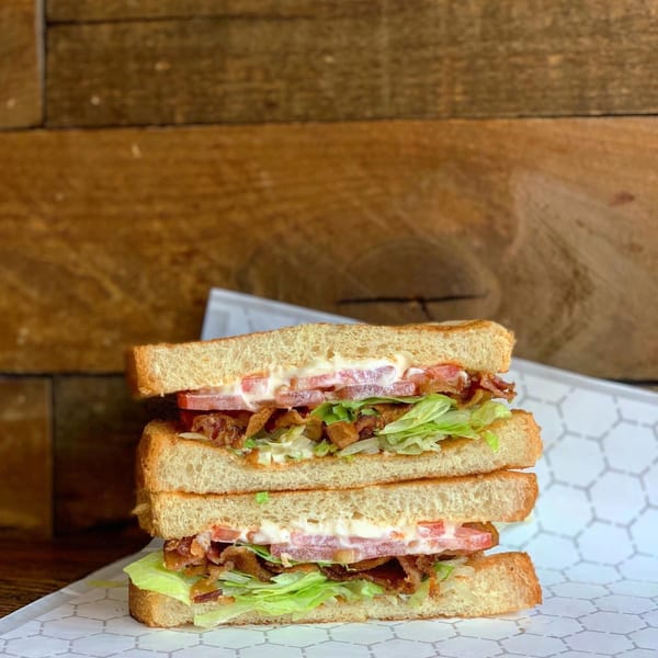 A stacked BLT sandwich with bacon, lettuce, tomato, and mayonnaise on toasted bread.